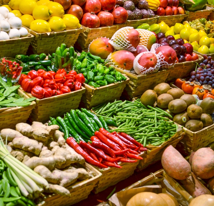 A diverse selection of fresh produce, including fruits and vegetables, is displayed in baskets at a market.