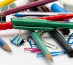 Various pens, pencils, paper clips, and binder clips in a pile